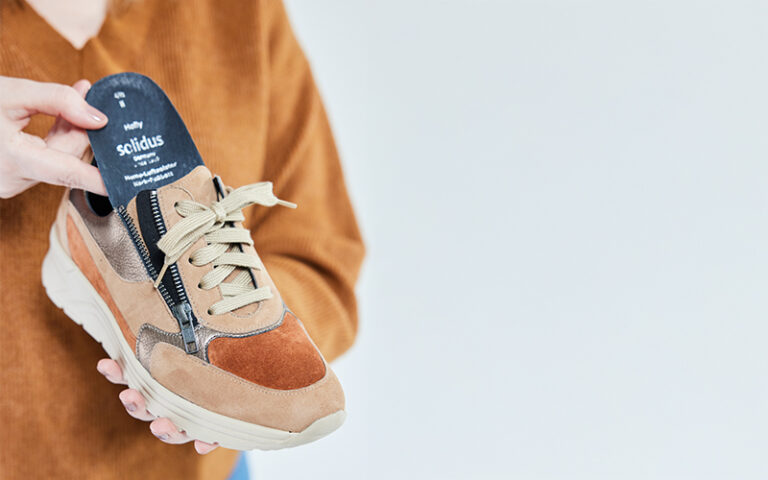 Solidus Holly 46023 Damen-Sneaker Farbe 30774 – Nahaufnahme in der Hand, seitlicher Reißverschluss geöffnet, Fokus auf Details und Komfor