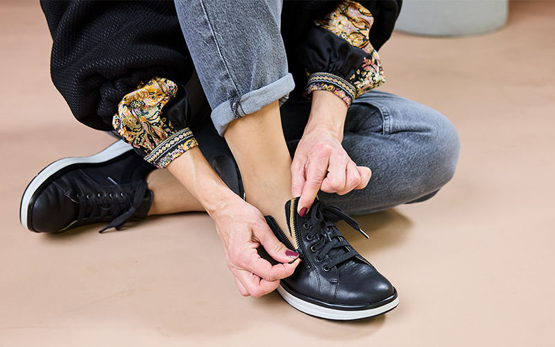 Solidus Karima 45031 Damen-Sneaker in Schwarz mit seitlichem Reißverschluss – Close-up beim Anziehen für alltagstauglichen Komfort