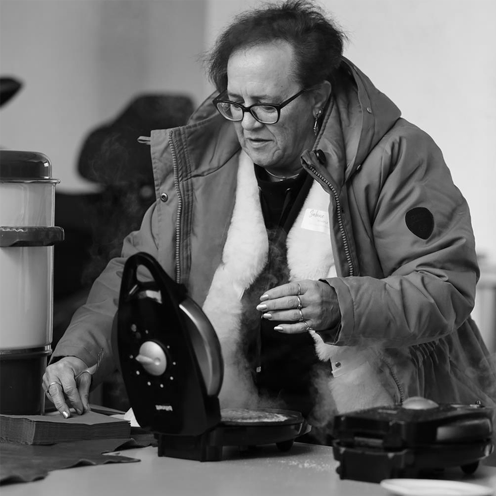 Mitarbeiterin backt Waffeln an der Station, Dampf steigt auf, Schwarzweiß