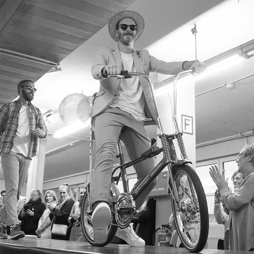 Mitarbeiter Michael Großmann fährt lässig mit Retro-Fahrrad über Laufsteg, Applaus, Schwarzweiß