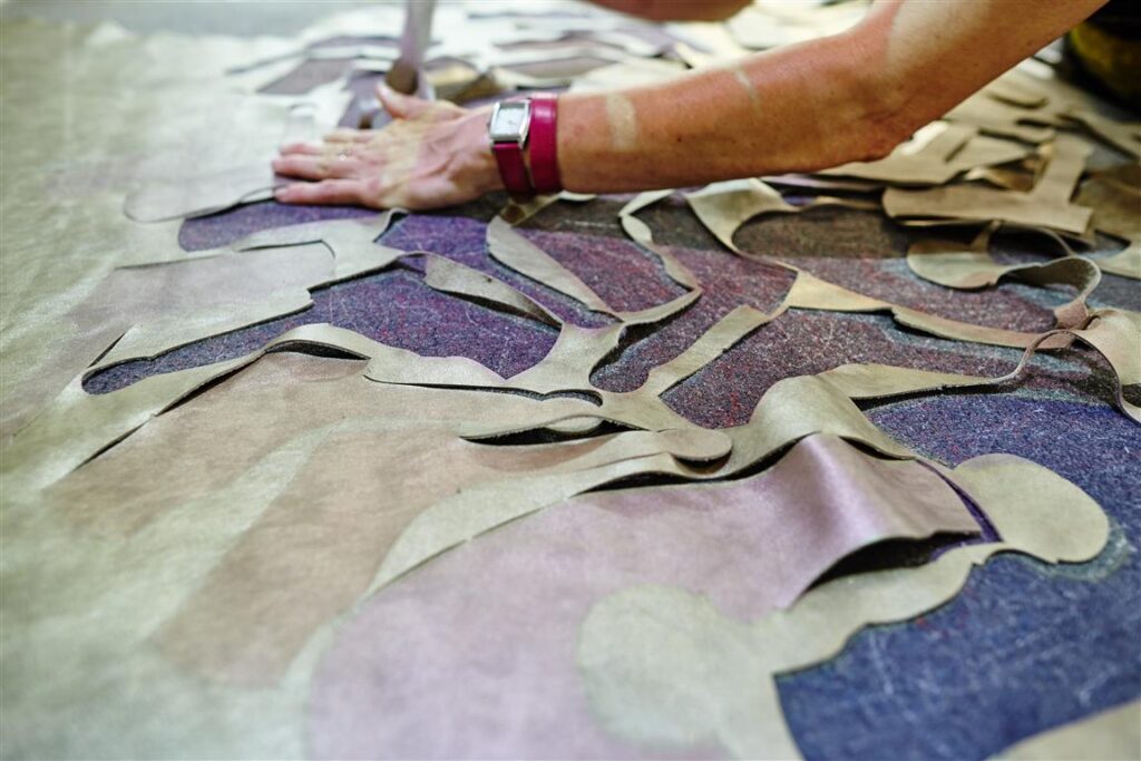 Zuschnitt in der Solidus Produktion: Lederteile liegen ausgebreitet auf dem Arbeitstisch, Hand sortiert die Stanzteile