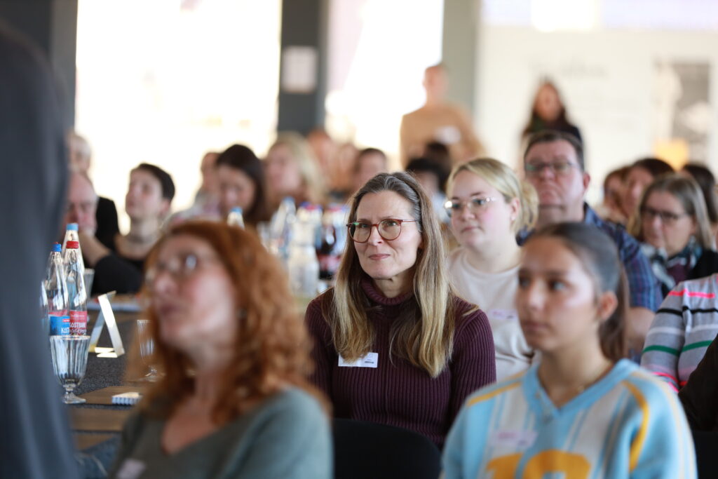 Teilnehmende der Solidus Academy sitzen im Seminarraum und hören aufmerksam zu, im Vordergrund eine Frau mit Brille