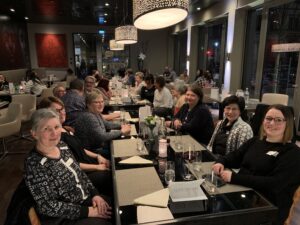 Gruppenfoto beim Solidus Academy Dinner: Teilnehmende sitzen gemeinsam im Restaurant an langen Tischen und lächeln in die Kamera