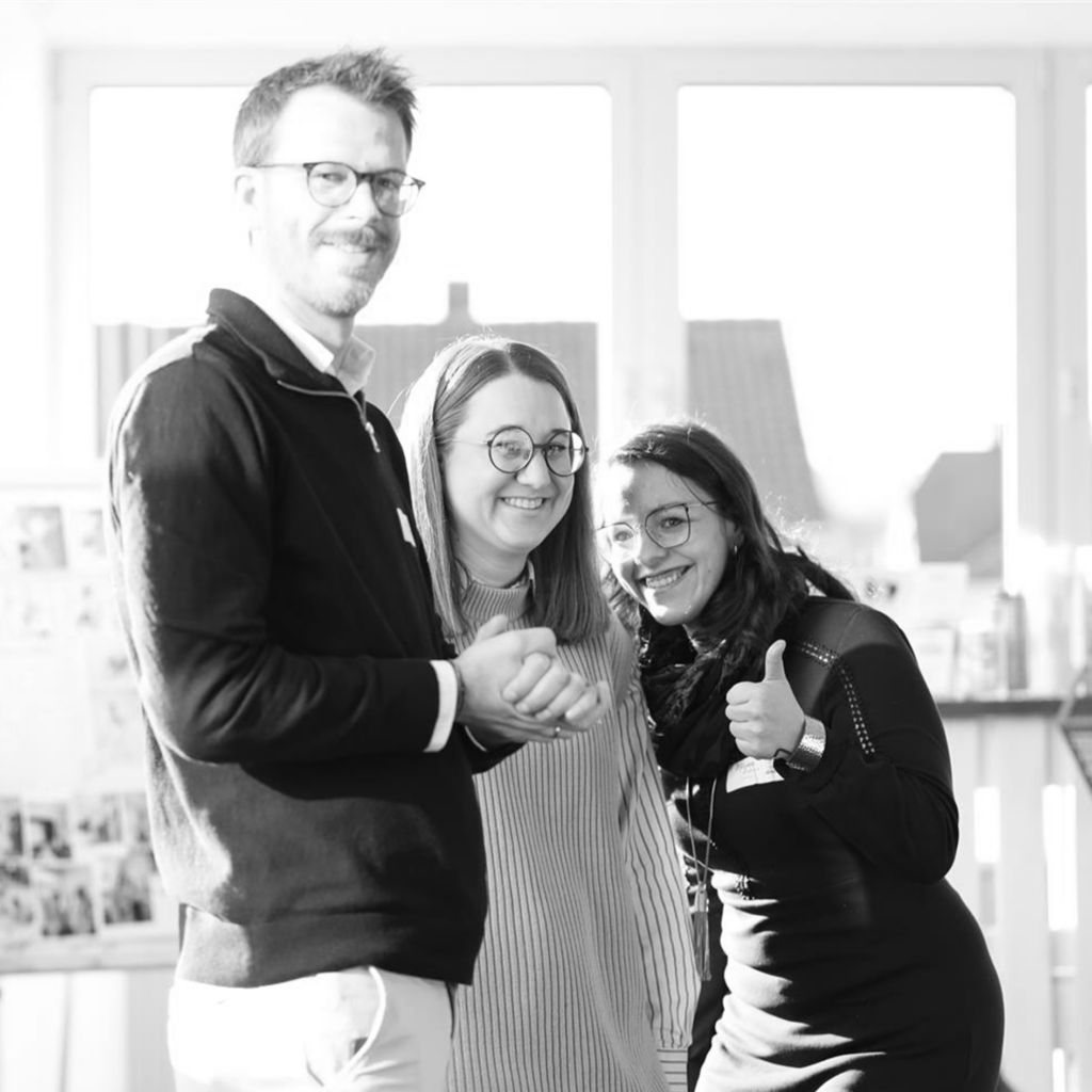 Michael Großmann mit dem Solidus Marketing-Team, schwarzweißes Teamfoto mit Daumen hoch im Büro