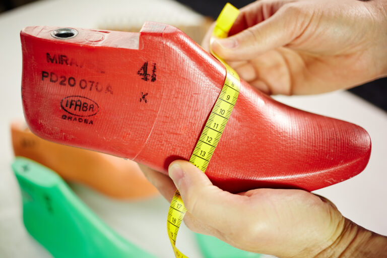 Leistenmessung bei Solidus: roter Schuhleisten wird mit Maßband vermessen – Basis für Passform und Komfort