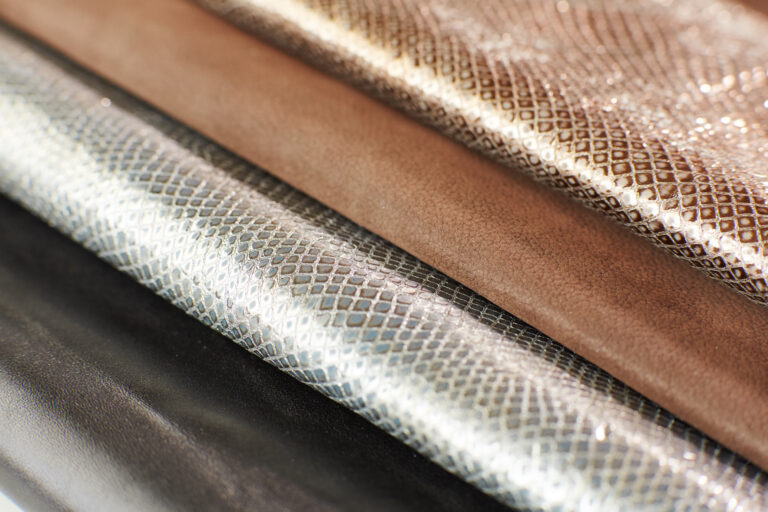 Nahaufnahme verschiedener Solidus Obermaterialien: metallisch schimmernde Leder mit Strukturprägung in Silber und Gold sowie braunes Glattleder