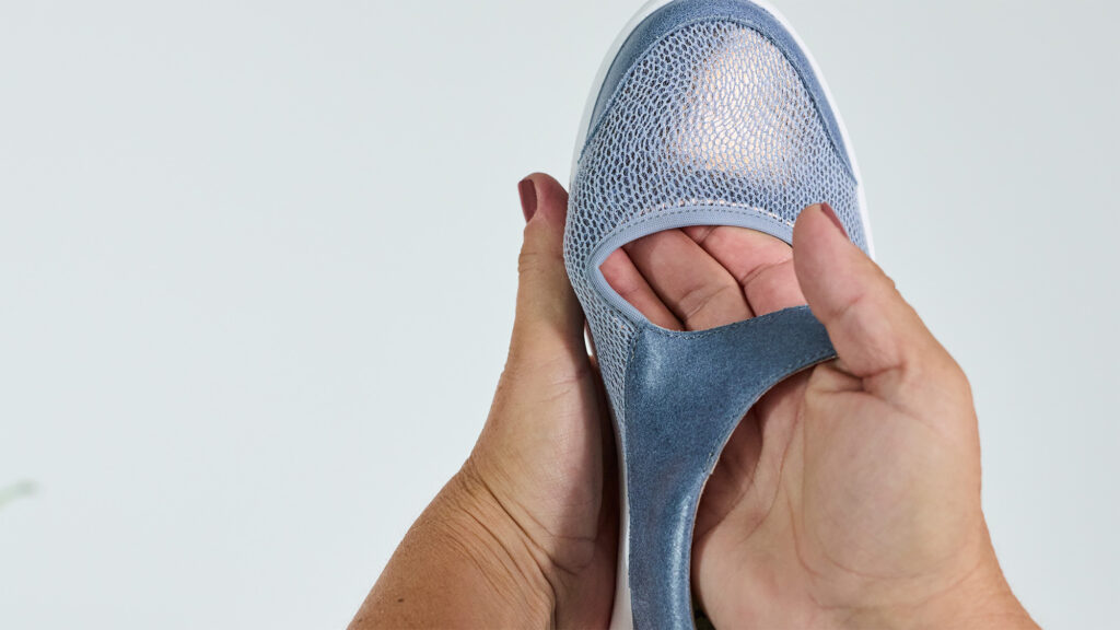 Hände zeigen das flexible Stretchmaterial eines hellblauen Solidus SolicareSoft Schuhs