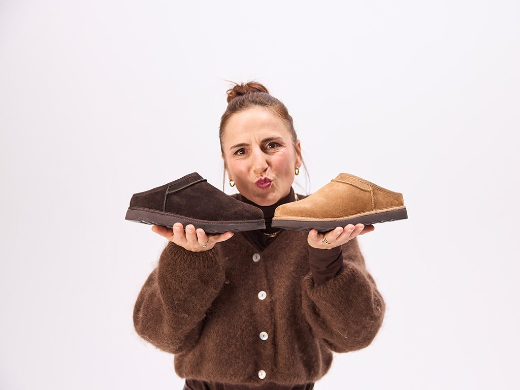 Frau hält zwei Solidus Hausschuhe aus Veloursleder in Braun und Cognac in den Händen – gemütliche Herbst/Winter Kollektion